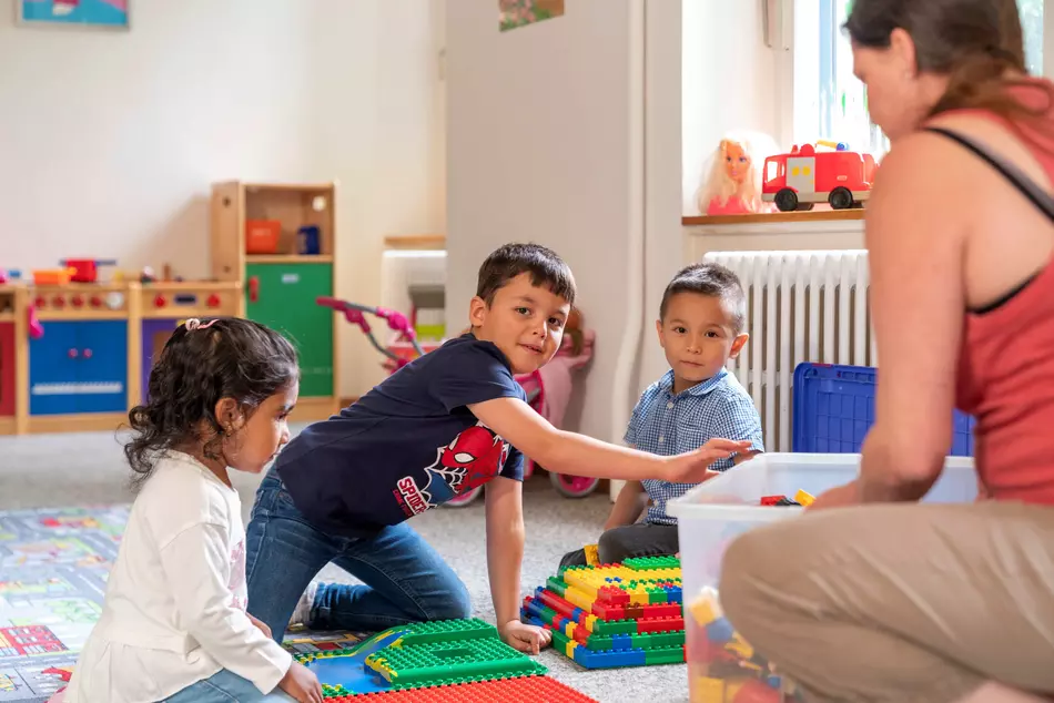 Des enfants jouent par terre en riant – image issue d’un projet de l’ONG HEKS.