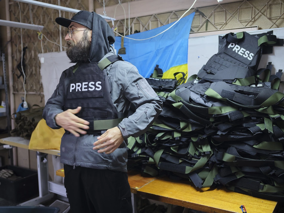 Informer en toute sécurité en Ukraine Un homme enfile un gilet portant l’inscription « PRESS » dans un atelier – une protection pour les personnes qui informent la population durant la guerre en Ukraine.