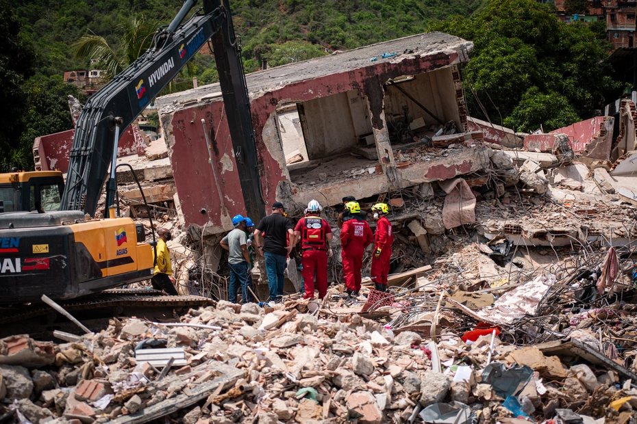 Des équipes de secours et une pelleteuse devant les décombres d’un bâtiment effondré après le séisme au Venezuela.