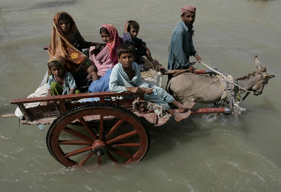 Un âne tire une charrette avec cinq enfants tandis qu'un homme marche à ses côtés dans les rues inondées lors des efforts d'aide humanitaire des inondations de 2010 au Pakistan.