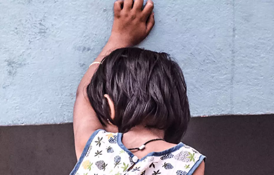 Un enfant appuyé contre un mur – un appel silencieux à la protection.