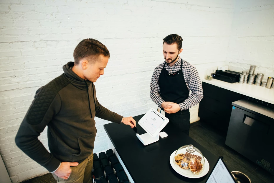 Dons des clients en point de vente Employé en caisse parlant au client : impliquez vos clients en transformant leurs points de fidélité ou leurs achats en soutien significatif.