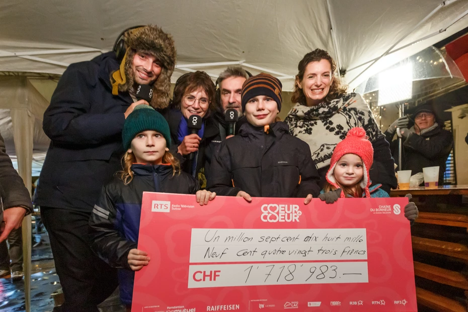 Dons des employés doublés Groupe tenant un gros chèque rouge : l'entreprise double les dons des employés pour un impact collectif accru.