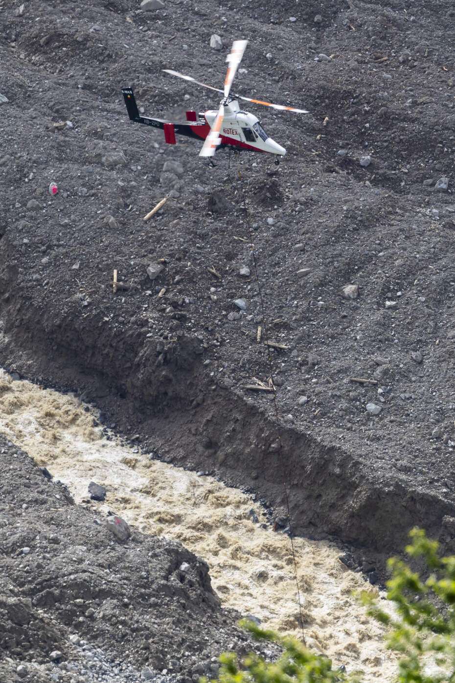 Transport aérien à Blatten : soutien aérien après un glissement de terrain Hélicoptère en mission au-dessus des éboulis et du torrent à Blatten - aide rapide après un glissement de terrain, dons urgents nécessaires.