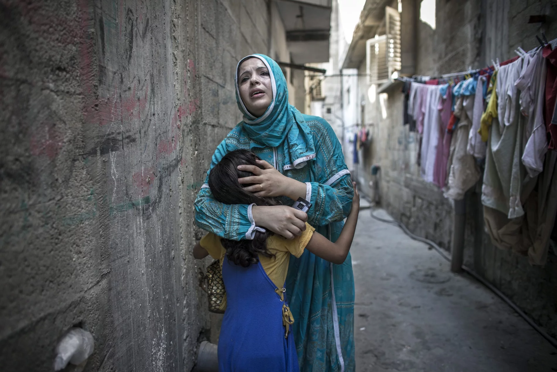 Femme portant son enfant en zone de guerre Une femme tient son enfant dans les bras – fuyant la guerre, elle a un besoin urgent d’aide humanitaire.