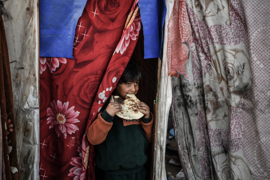 Garçon à Gaza mangeant du pain Un garçon à Gaza mange du pain – les dons assurent une aide alimentaire essentielle dans une zone de crise.