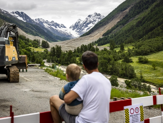 Blatten après le glissement de terrain : regard sur un avenir incertain Un père et son enfant regardent la zone du glissement de terrain à Blatten - donner de l'espoir en aidant et en soutenant sur place.