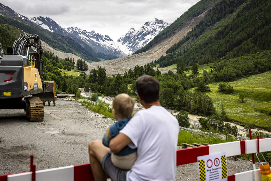 Blatten après le glissement de terrain : regard sur un avenir incertain Un père et son enfant regardent la zone du glissement de terrain à Blatten - donner de l'espoir en aidant et en soutenant sur place.