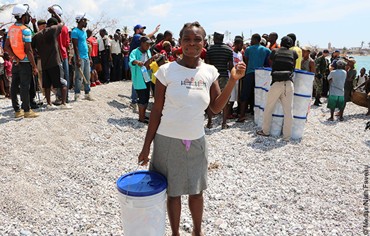 Eine Frau hält einen Eimer mit Hilfsgütern in den Händen, die sie nach dem Wirbelsturm Matthew erhalten hat.