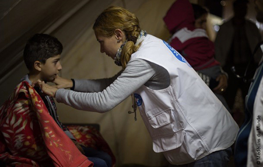 Eine Mitarbeiterin von unserem Partner Médecins du Monde behandelt einen Flüchtlingsjungen in einem Flüchtlingslager in Griechenland